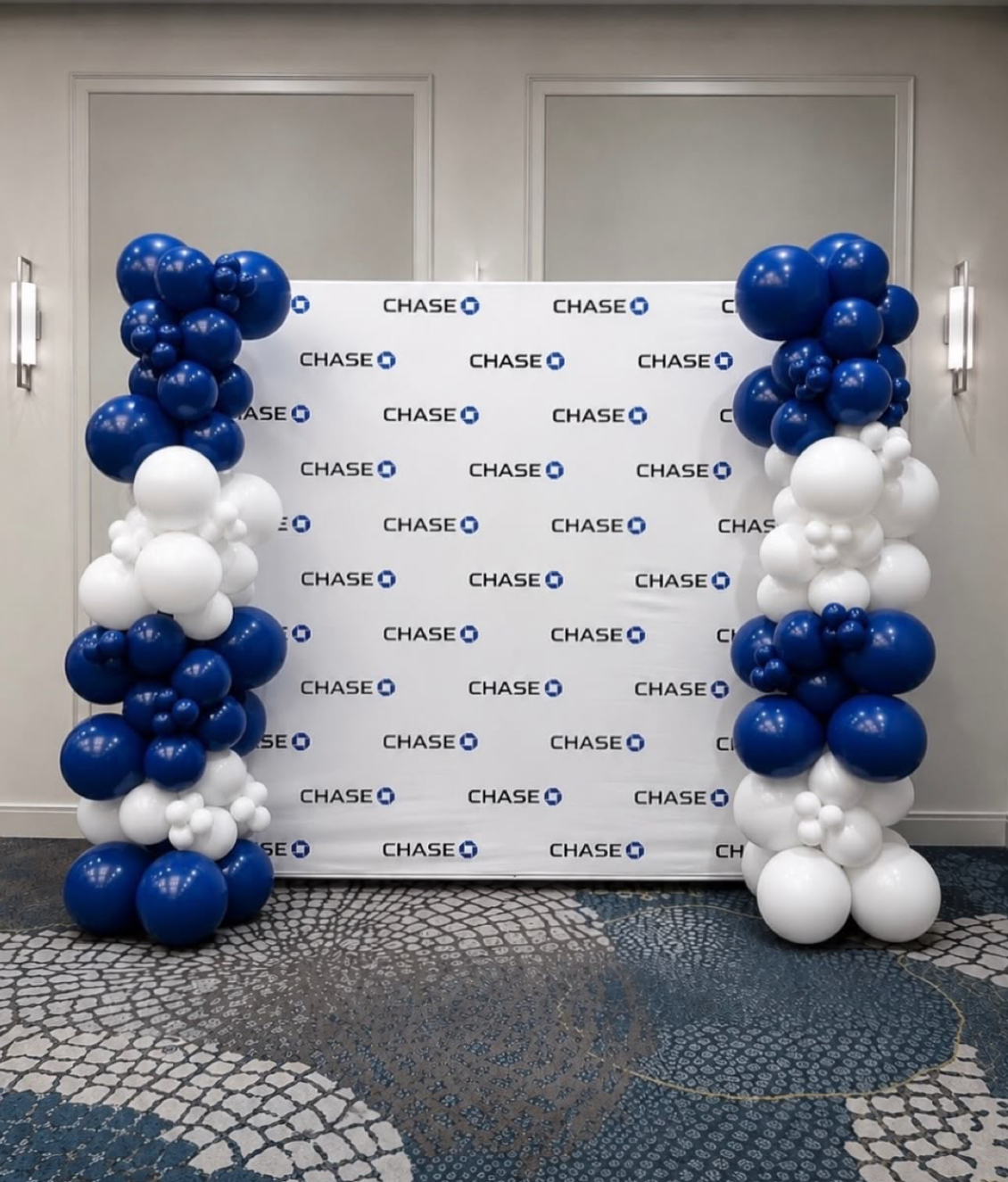 Navy and white balloon columns flanking a Chase branded step-and-repeat backdrop